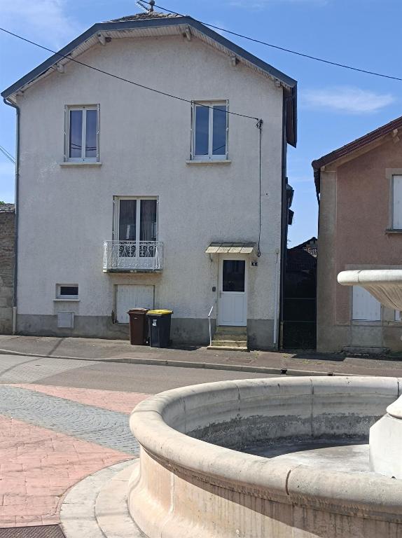 une maison blanche avec une fontaine devant elle dans l'établissement Gîte de la fontaine, à Venarey-les-Laumes
