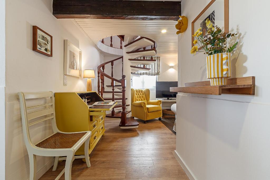 ein Wohnzimmer mit gelben Stühlen und einer Wendeltreppe in der Unterkunft Villa Mau Maria incl Parking by Home Sweet Home Aveiro in Aveiro