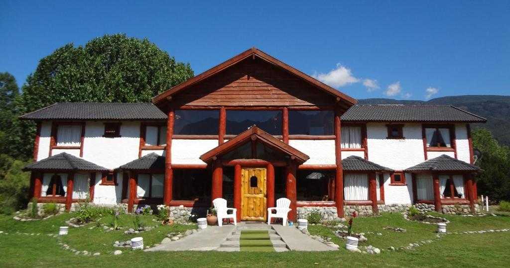 a large wooden house with a yellow door at Complejo Turístico Sol de Puelo in Lago Puelo