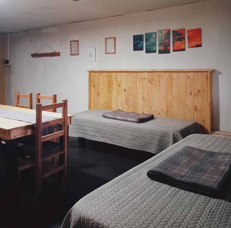 a room with two beds and a wooden wall at Tierras Mágicas in Villa Pehuenia