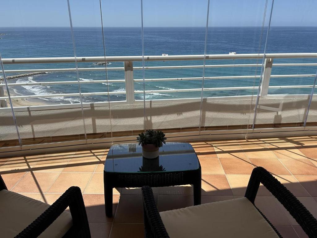Un balcón con mesa y sillas y el mar. en Playa de Oro 14C, en Calpe