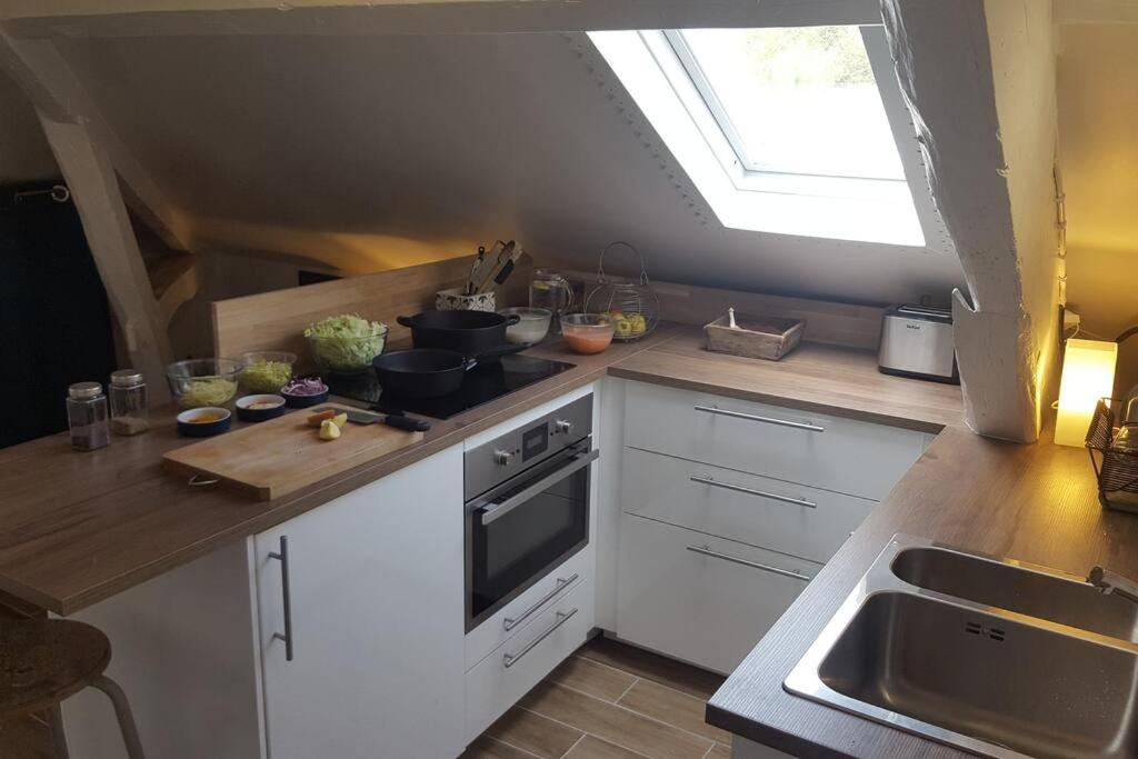 une cuisine avec des armoires blanches, un évier et une fenêtre dans l'établissement Studio cosy au calme à Meudon, à Meudon