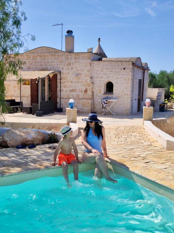 a woman and a child sitting in a swimming pool at Trullo Bubamare in San Michele Salentino
