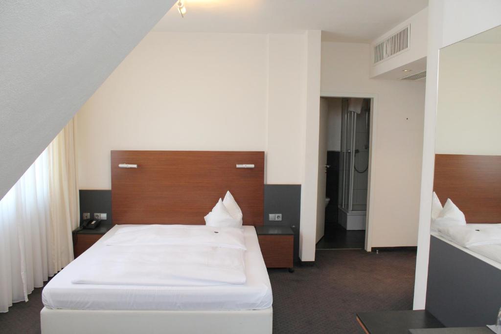 a hotel room with a white bed and white walls at Hotel am Hirschgarten in Filderstadt