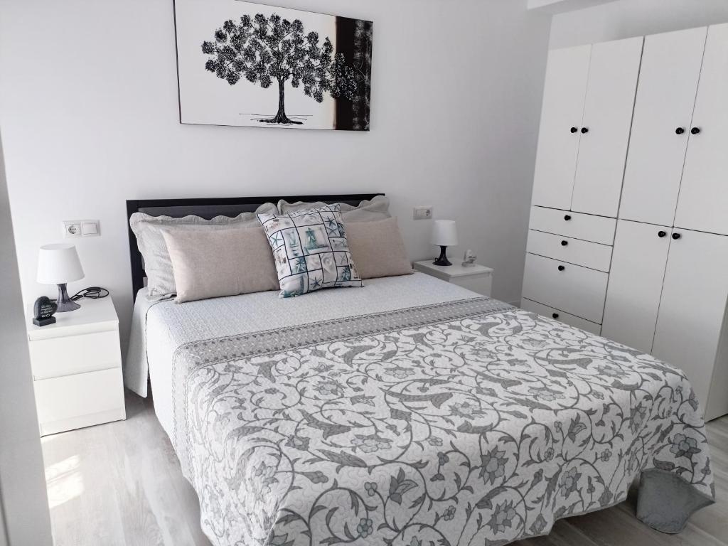 ein Schlafzimmer mit einem Bett mit einem Baum an der Wand in der Unterkunft Mare de Deu, vivienda vacacional para familias y mayores de 25 años en el Grao de Gandia-Playa in Puerto de Gandía