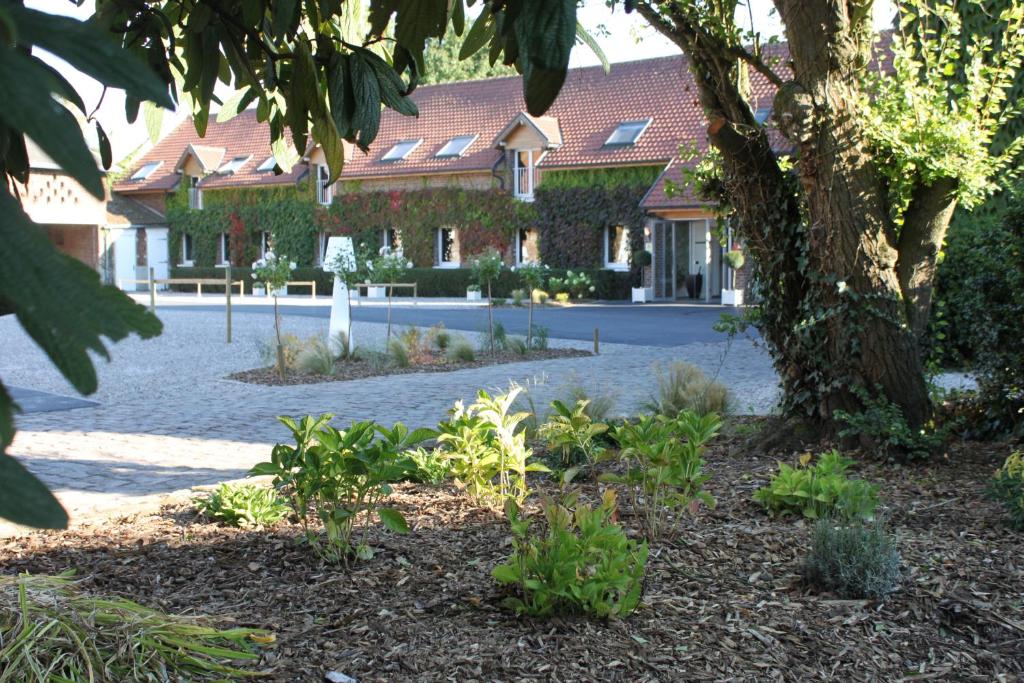 un edificio con un patio con plantas delante de él en LOGIS Hôtel & Restaurant - Le Manoir de Gavrelle en Gavrelle