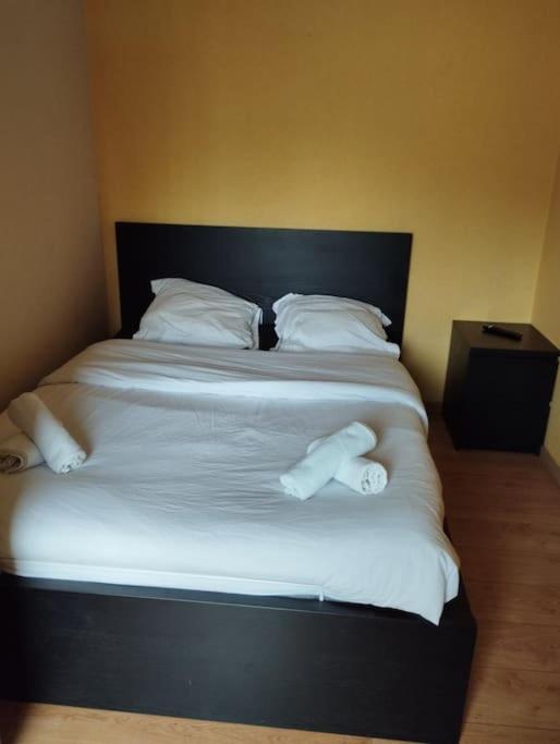 Elle comprend un grand lit avec des draps et des oreillers blancs. dans l'établissement Appartement place Keruscun, à Brest