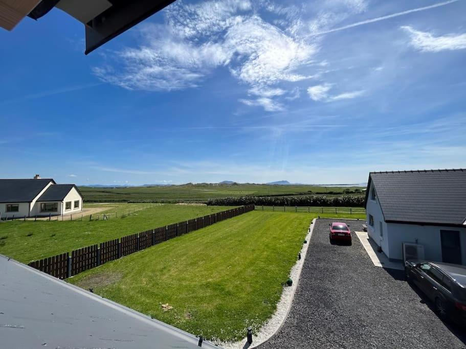 una casa con un'auto parcheggiata accanto a un campo di Bobbys Studio a Belmullet