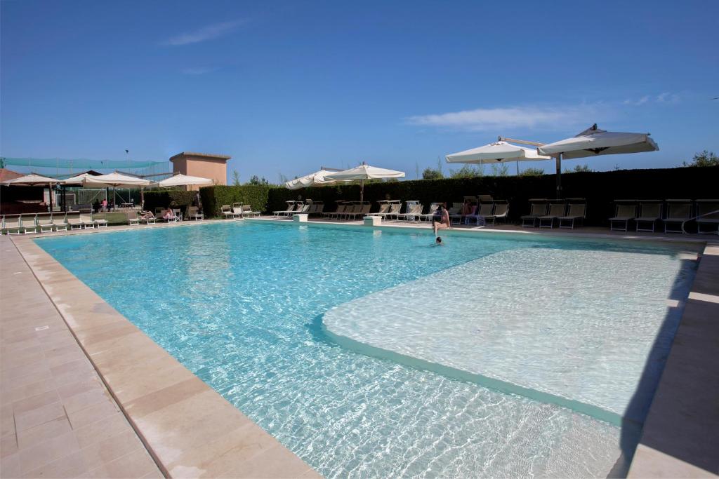 a large swimming pool with chairs and umbrellas at Resort Capalbio in Capalbio