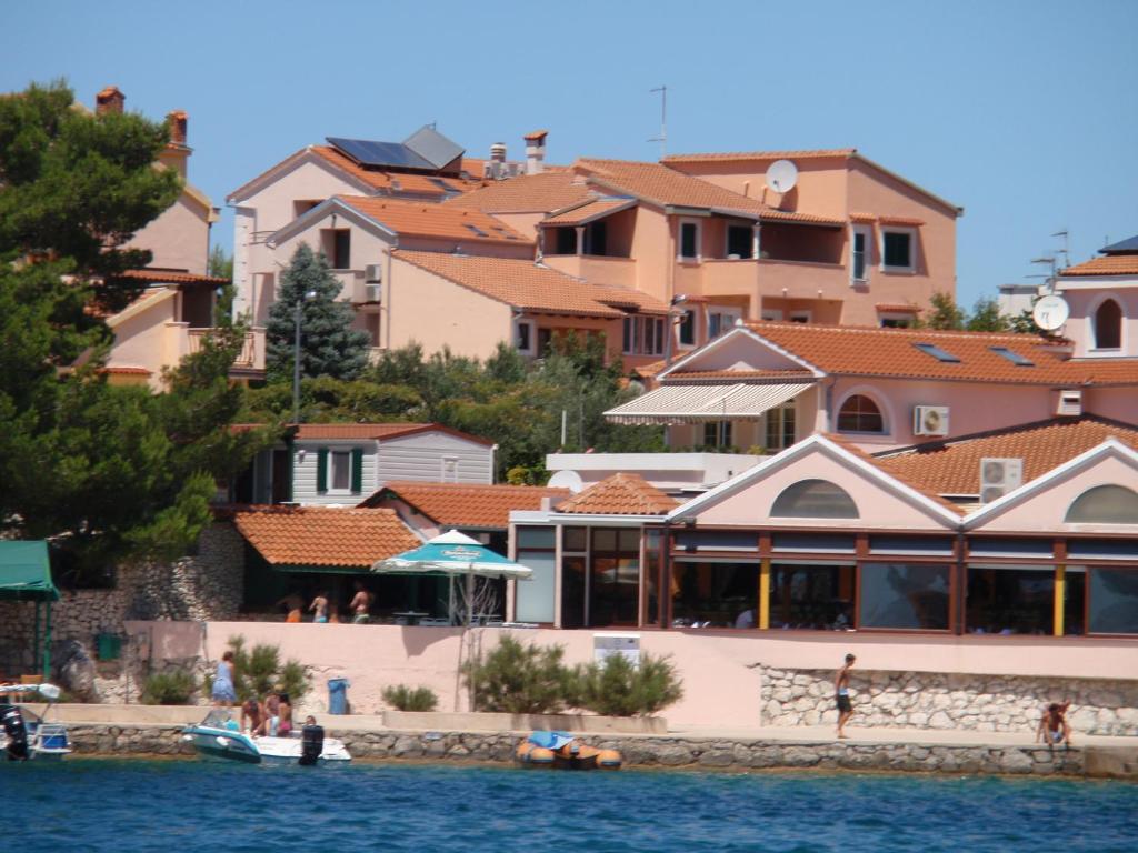 un groupe de bâtiments à côté d'une masse d'eau dans l'établissement Villa Rosa, à Brodarica