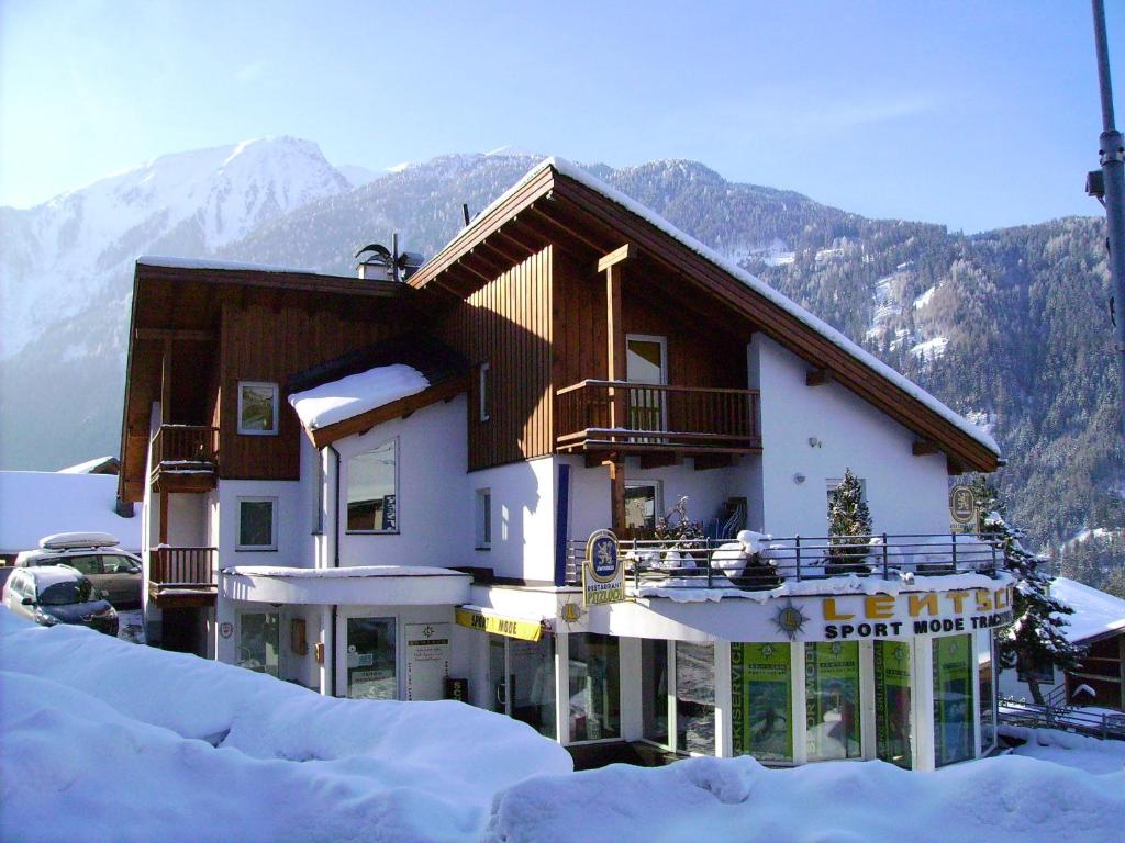 un edificio en la nieve con montañas en el fondo en Pepis Ferienwohnungen inklusive Sommercard, en Jerzens
