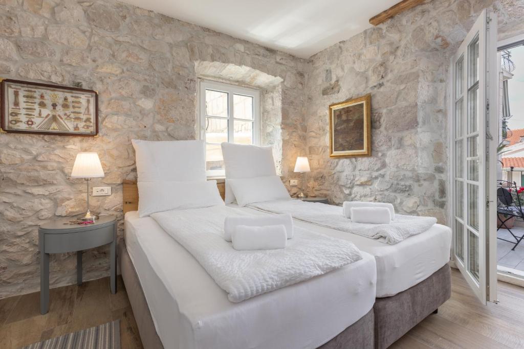 two beds in a room with a stone wall at NEW - Casa Columba - 4 Star Design Boutique Hotel with Outdoor Pool & Private Garden in Makarska