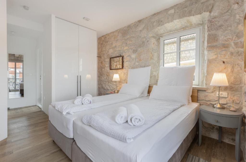 a bedroom with two beds and a stone wall at NEW - Casa Columba - 4 Star Design Boutique Hotel with Outdoor Pool & Private Garden in Makarska