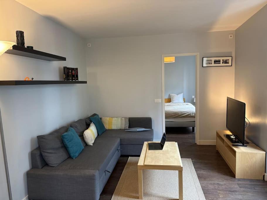 - un salon avec un canapé gris et un lit dans l'établissement Cocon contemporain et confortable proche Paris, à Alfortville