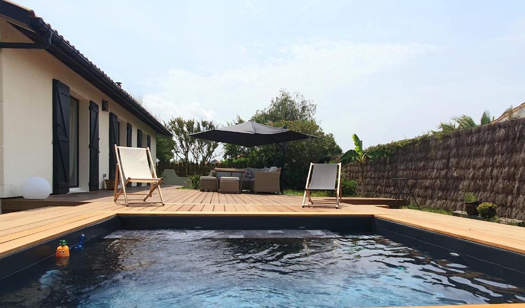 une piscine avec deux chaises et un parasol dans l'établissement Le cocon de Bali, à Gujan-Mestras