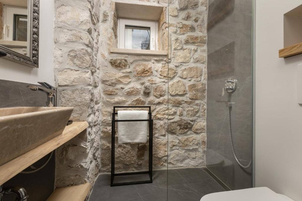 a bathroom with a glass shower with a stone wall at NEW - Casa Columba - 4 Star Design Boutique Hotel with Outdoor Pool & Private Garden in Makarska