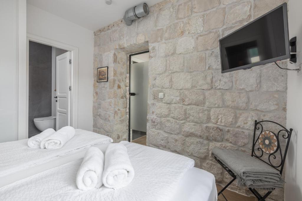 a bedroom with two beds and a tv on a stone wall at NEW - Casa Columba - 4 Star Design Boutique Hotel with Outdoor Pool & Private Garden in Makarska