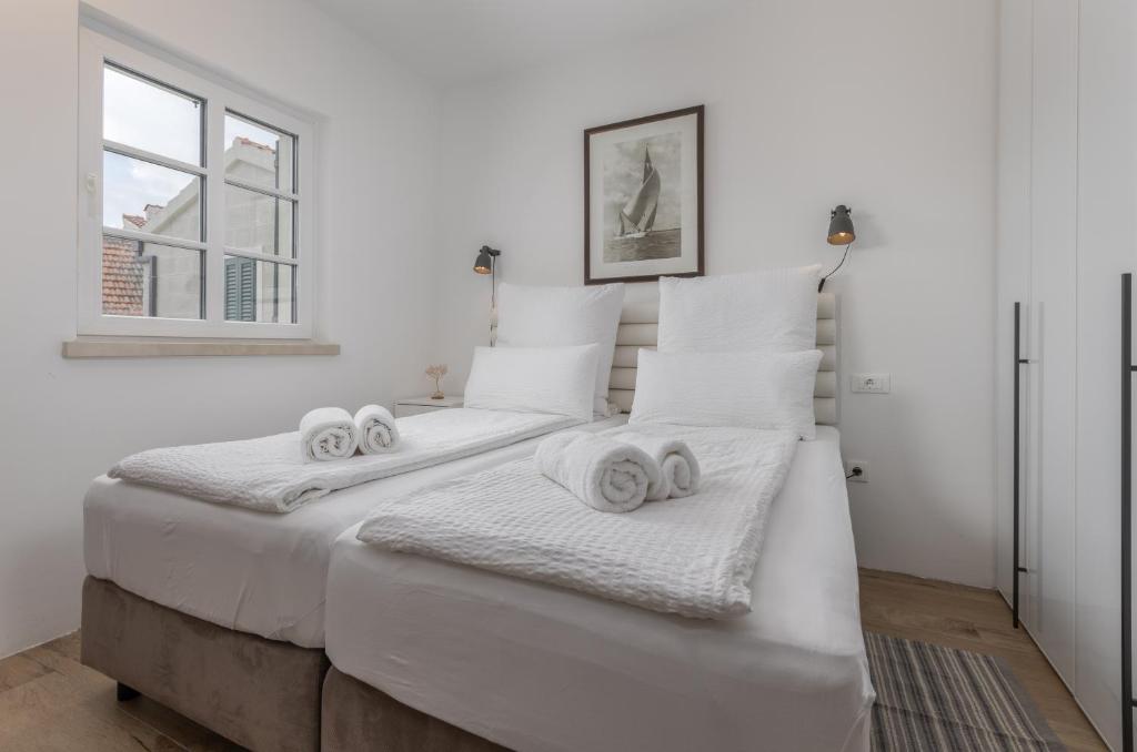 a white bedroom with two beds with towels on them at NEW - Casa Columba - 4 Star Design Boutique Hotel with Outdoor Pool & Private Garden in Makarska