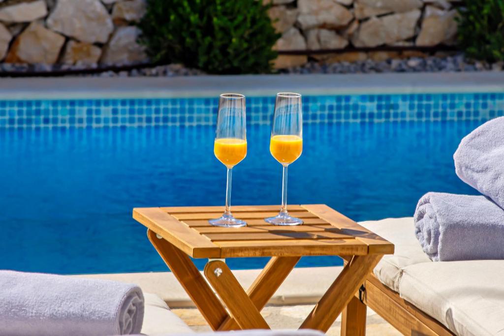 two glasses of wine on a table next to a pool at Villa Mare in Vinišće