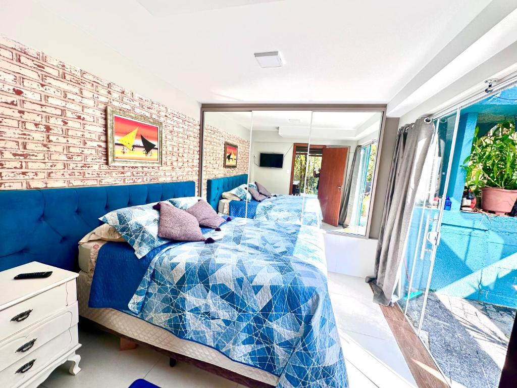 a bedroom with a blue bed and a brick wall at RECANTO DOS PASSARINHOS LINDA CASA COM 2 quartos in Balneário Camboriú