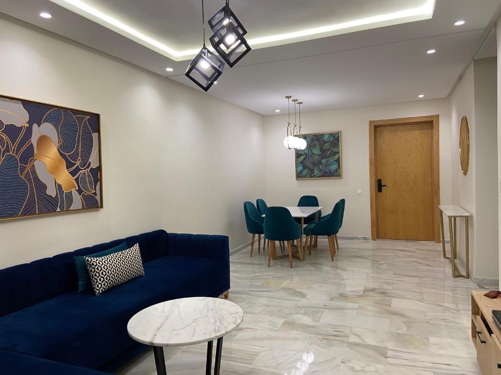Una sala de estar con un sofá azul y una mesa. en Luxueux Appart à 5 min aéroport mohamed 5, en Nouaceur