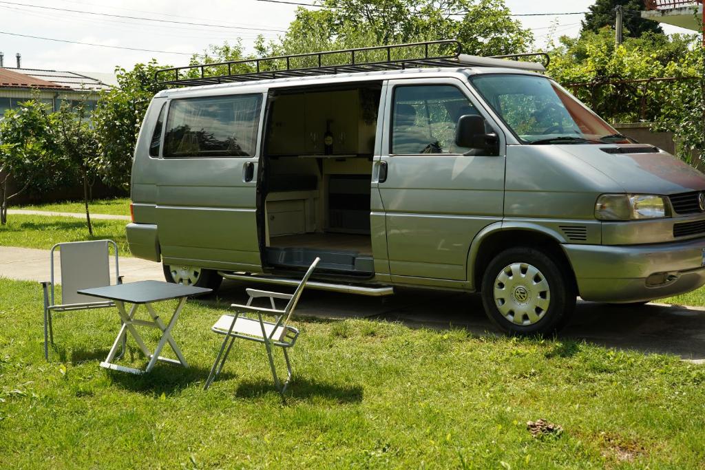 a green van parked in the grass with a table and chairs at Montenegro Camper VOYAGER in Podgorica