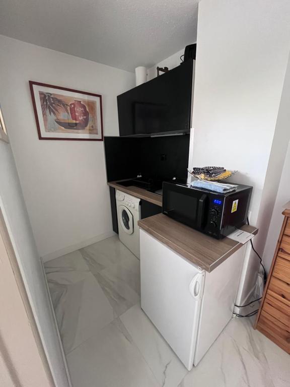 a small kitchen with a microwave and a refrigerator at Studio en résidence avec parking in Cap d'Agde