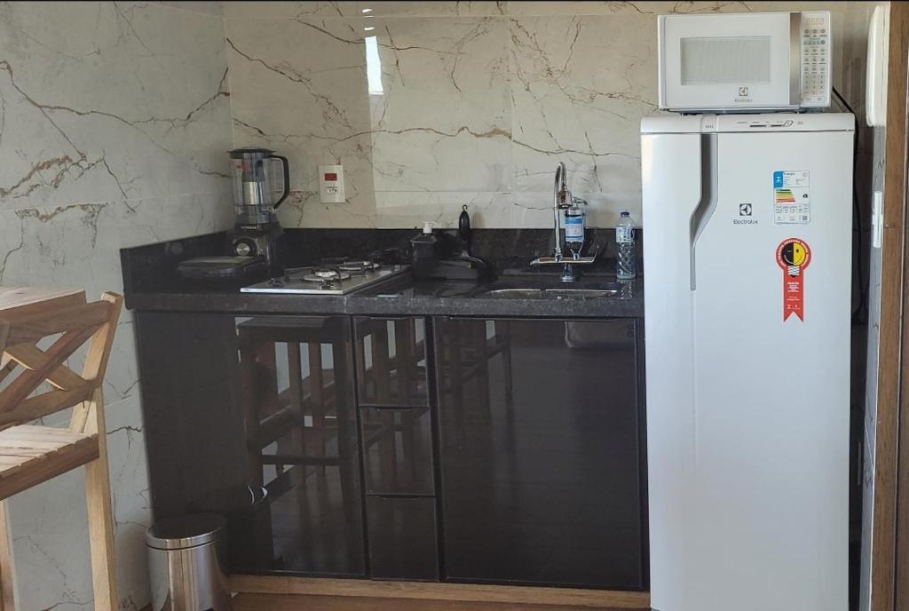 a kitchen with a refrigerator and a counter with a microwave at Chalé Campo Florido in São Roque de Minas