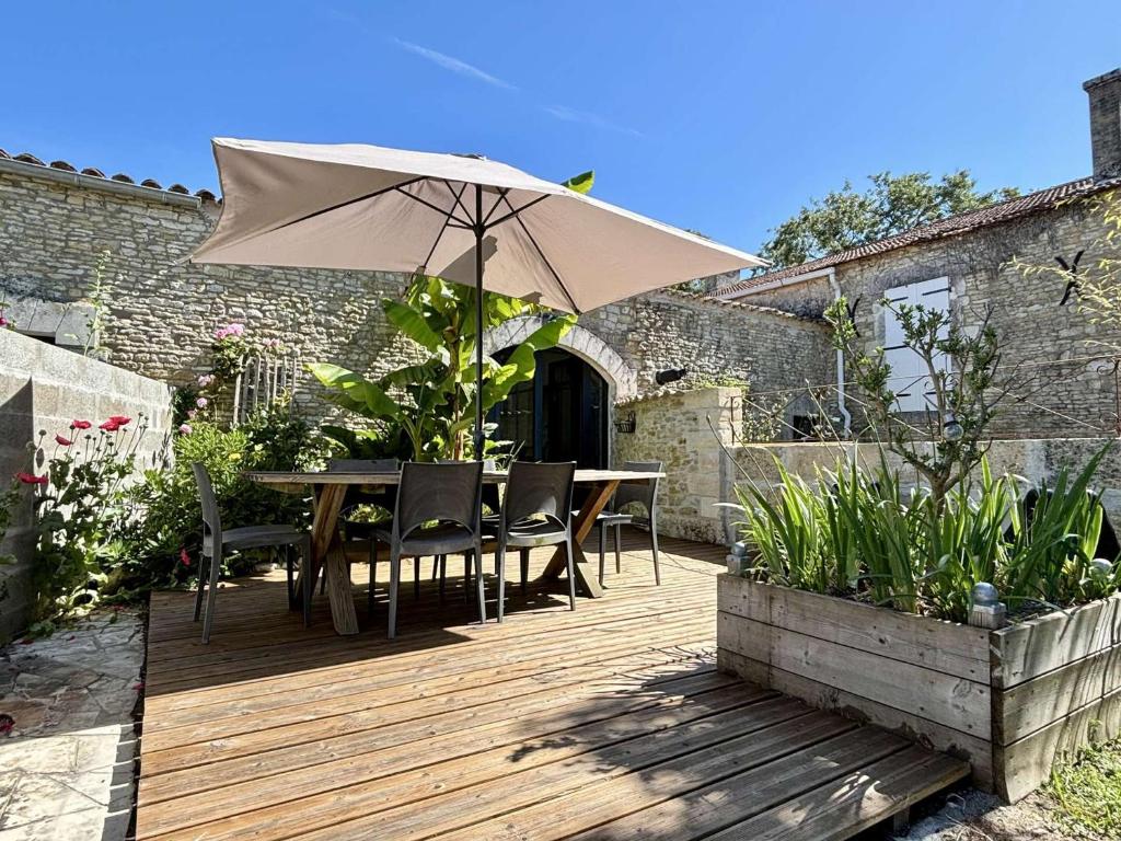 une terrasse en bois avec une table et un parasol dans l'établissement Maison rénovée près de la plage, jardin privé et terrasse - 4 couchages - FR-1-246A-321, à Saint-Georges-dʼOléron