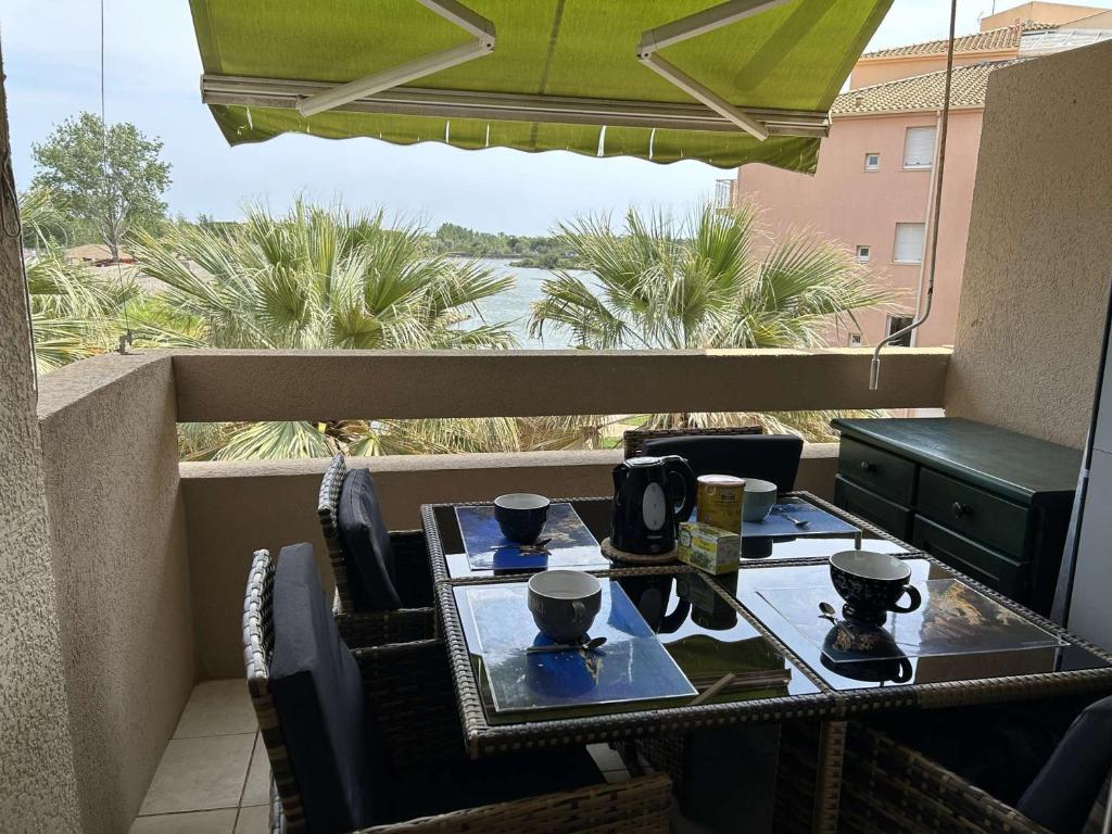 une table avec des tasses à café au sommet d'un balcon dans l'établissement Appt 2P 6 pers avec piscine et parking à Port Camargue - FR-1-250-288, au Grau-du-Roi