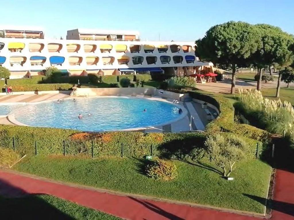 une grande piscine devant un immeuble dans l'établissement Studio refait avec piscine et clim, proche plage et commerces - FR-1-731-81, au Grau-du-Roi