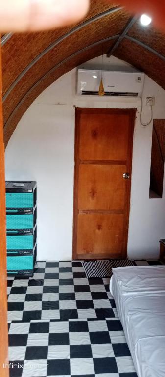 une pièce avec une porte et un sol à carreaux noirs et blancs dans l'établissement Samalas Syariah Cottage, à Seganteng