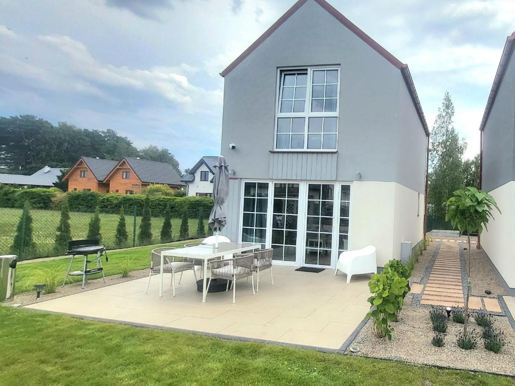 a white house with a table and chairs in the yard at Na Pokładzie in Dębki