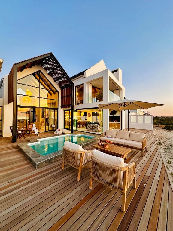 a house with a swimming pool on a wooden deck at Thalassophile Beach House - Heated Pool in St. Helena Bay