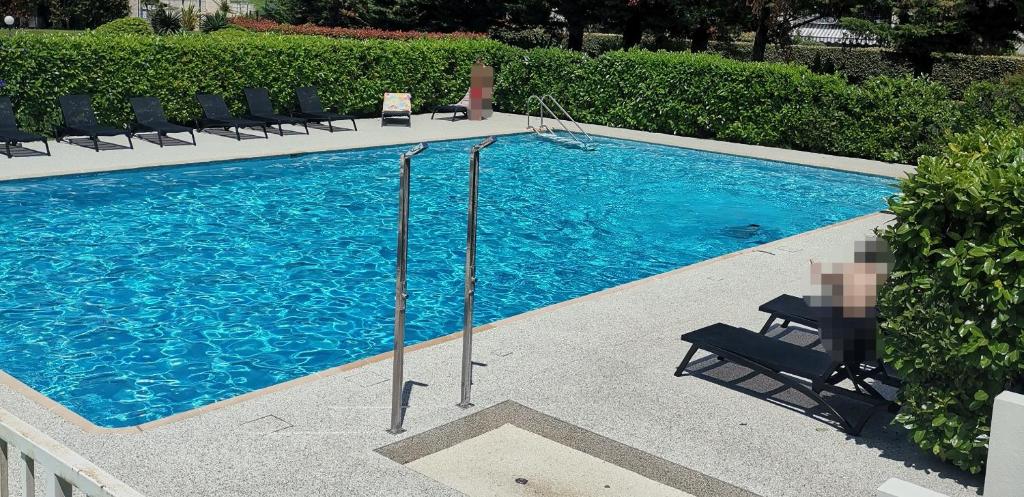 une grande piscine bleue avec des chaises et des buissons dans l'établissement Lido, private apartment seaside, parking, swimming pool, à Cagnes-sur-Mer