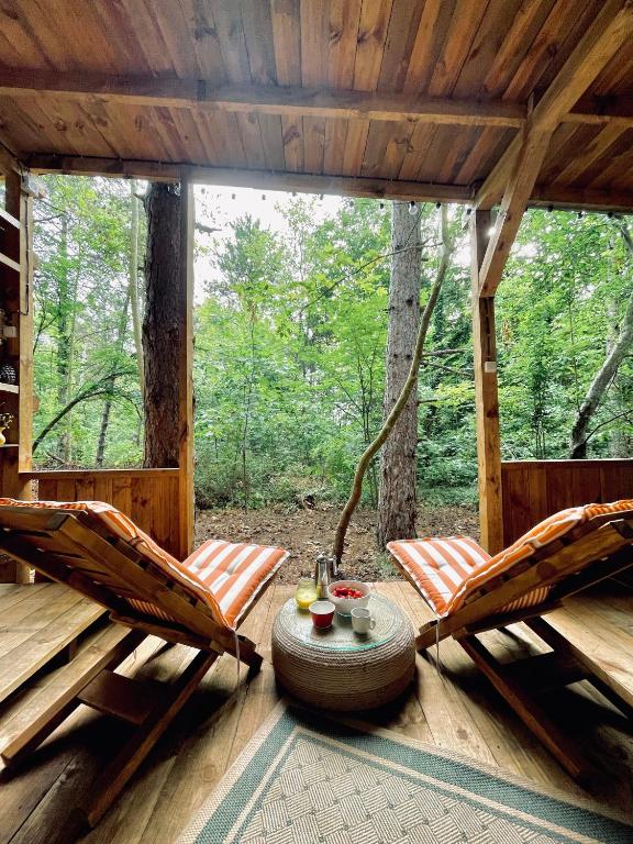 a porch of a cabin with two chairs and a table at Каравана Безвремие in Chernomorets