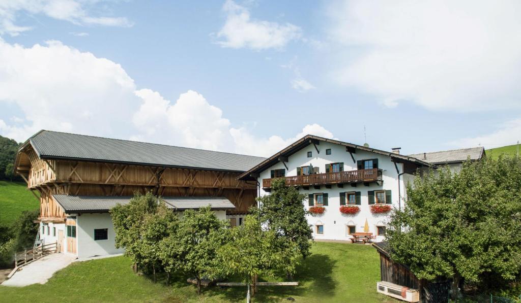 a large white building with a black roof at Kreuzerhof in Siusi