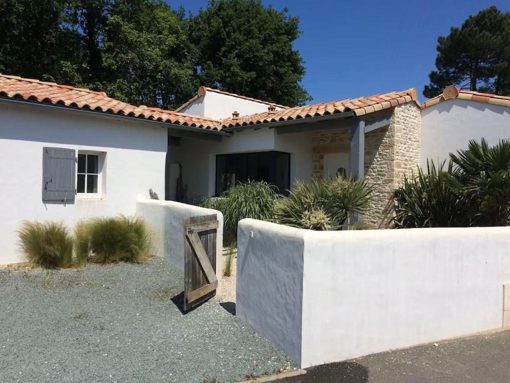 une maison blanche avec une porte en bois devant elle dans l'établissement Villa Taru La Palmyre, aux Mathes