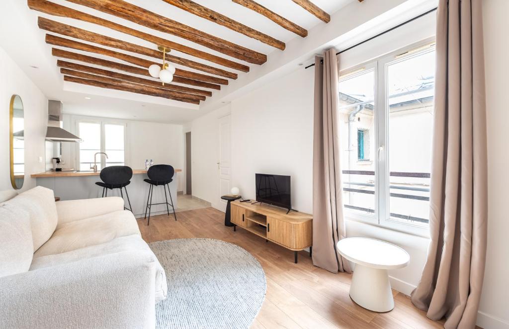 un salon avec un canapé blanc et une télévision dans l'établissement Montparnasse - Studio Fully equipped, à Paris