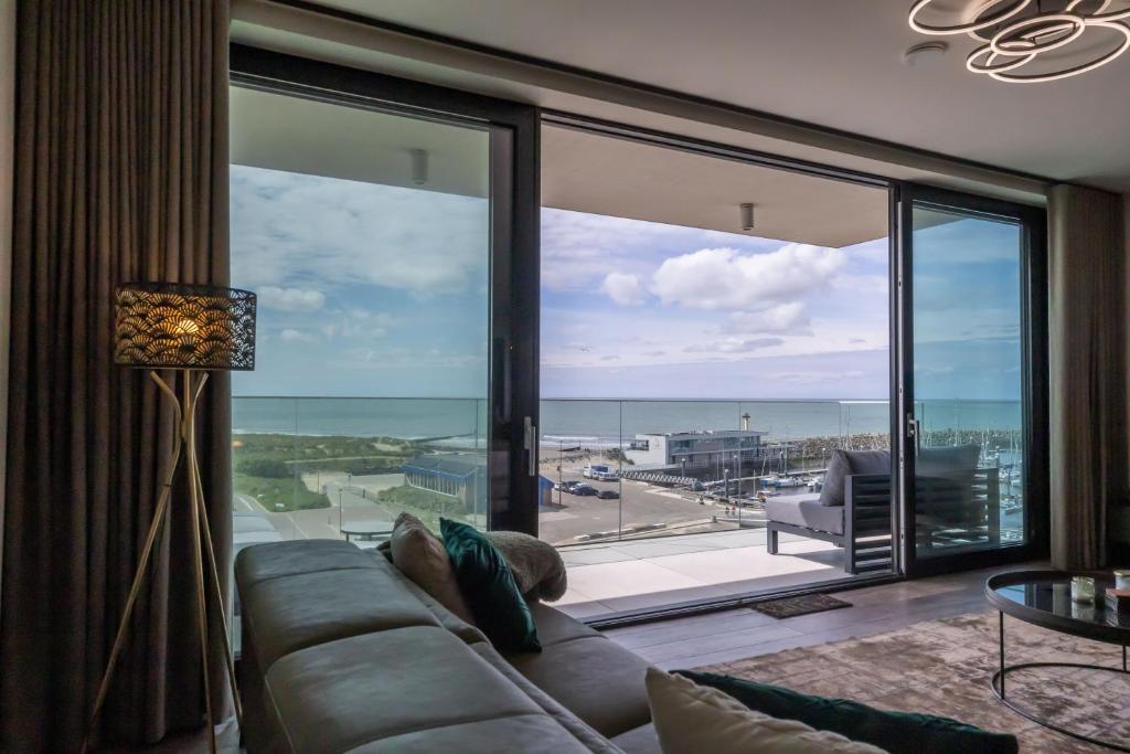 a living room with a couch and a large window at Côte de la Mer, Ultra Luxurious, Sea View, use of shared pool and sauna in Cadzand