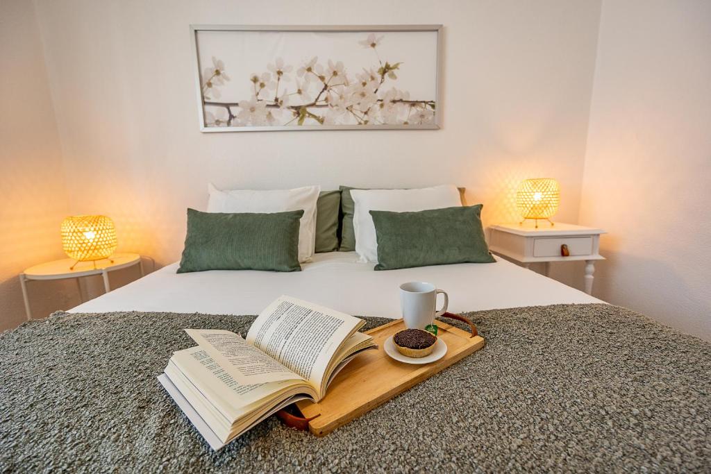 a bed with a tray with books and a cup and a coffee mug at Casa da Vigia by StaySalmar in A dos Cunhados