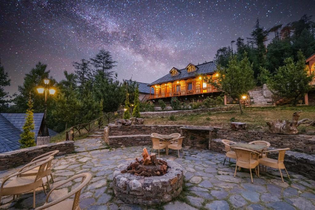 a house with a fire pit in the yard at night at WoodVista Cottages By Jomotel in Shimla