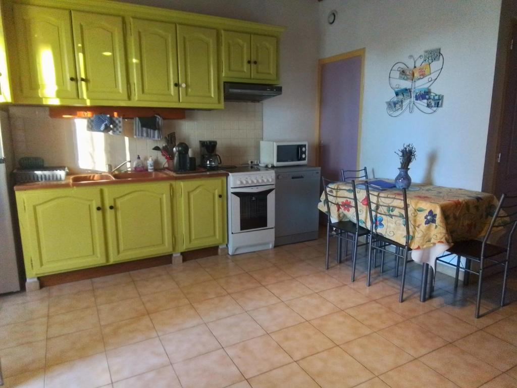 une cuisine avec des armoires jaunes et une table avec des chaises dans l'établissement Appartement indépendant dans mas, à Arles