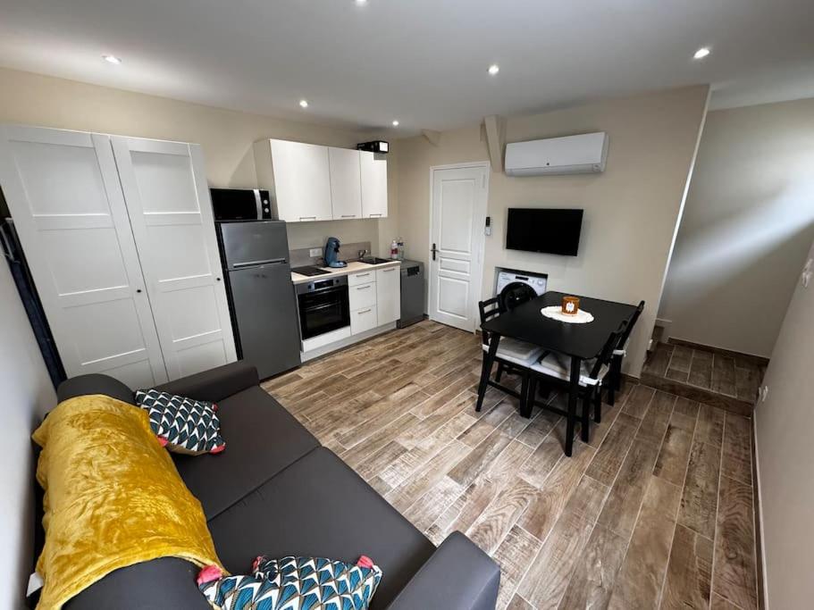 Una sala de estar con un sofá y una mesa y una cocina. en maison de la marine, en Dives-sur-Mer