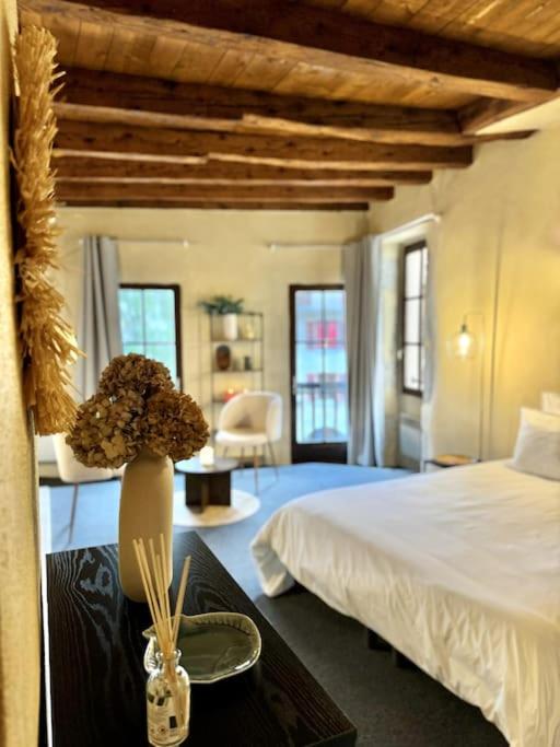 - une chambre avec un lit et un vase avec des fleurs sur une table dans l'établissement Cocon au coeur de la vieille ville, à Annecy