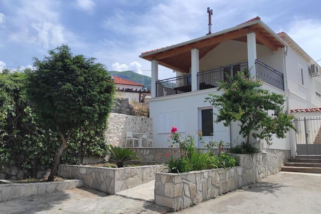a white house with a balcony and trees at Bungevilia Apartment in Gruda