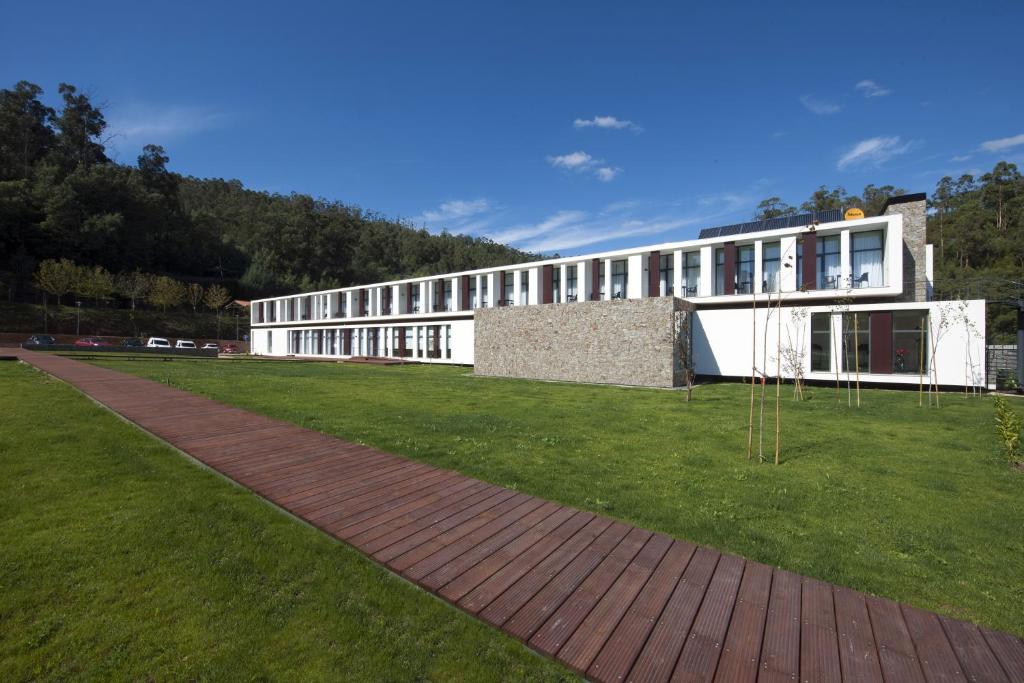 um edifício com um campo relvado à sua frente em Hotel Parque Serra da Lousã em Miranda do Corvo