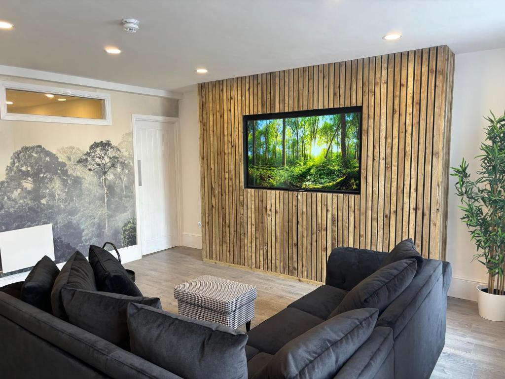 een woonkamer met twee banken en een televisie aan de muur bij Williamson Suites - Apartment 1 in Liverpool