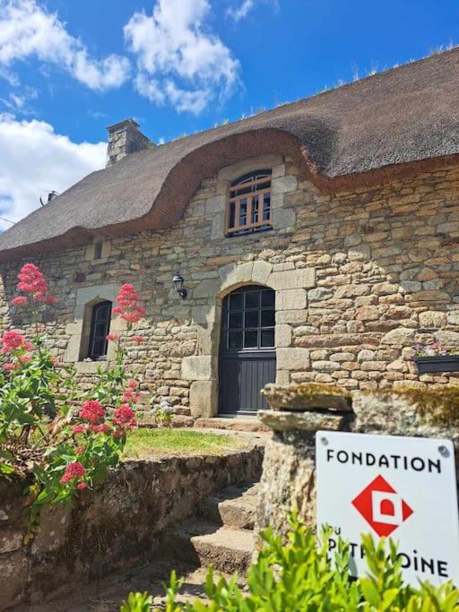 une maison en pierre avec un panneau devant elle dans l'établissement Gîte Chaumière de Floranges 6 personnes Morbihan, à La Chapelle-Neuve