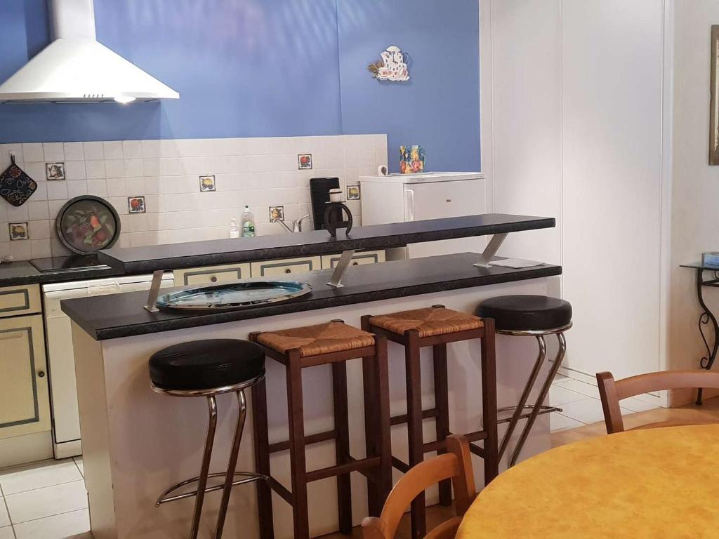 - une cuisine avec un comptoir et quelques tabourets dans l'établissement Appartement T2 cosy, 52m², 4-5 pers, centre ville Cauterets, tout équipé - FR-1-234-305, à Cauterets
